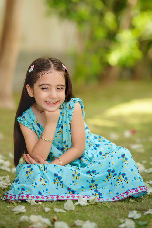 Smiling girl in blue floral dress sitting on grass, perfect for kids' summer fashion