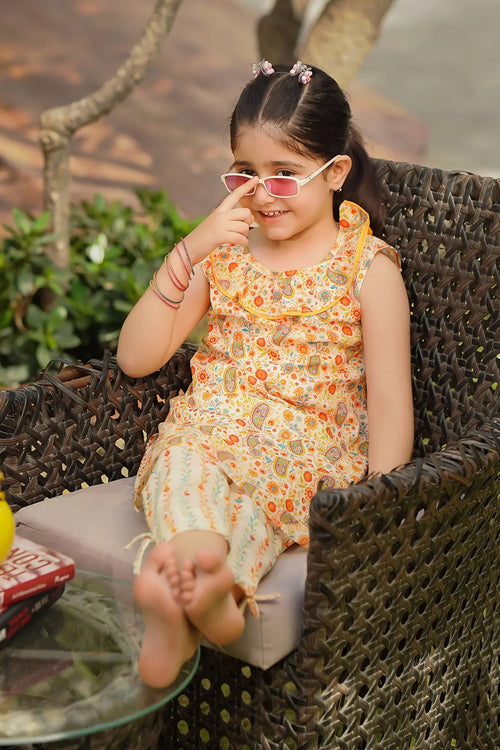Cute girl in floral print dress with ruffled collar, wearing sunglasses, sitting on wicker chair outdoors