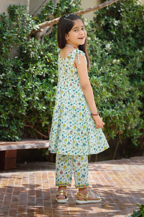Girl in floral print dress and matching pants, outdoor garden setting, trendy kids fashion