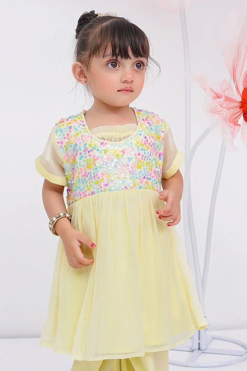 Little girl in yellow sequin top and tulle skirt, trendy kids fashion outfit