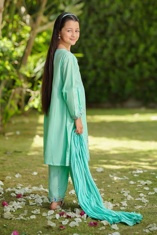Girl in mint green embroidered kurta set with matching dupatta, standing outdoors on grass with flower petals.