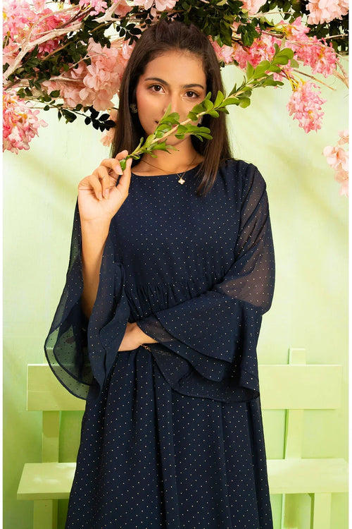 Navy blue polka dot dress with sheer sleeves, styled with greenery and pink flowers for a trendy look.