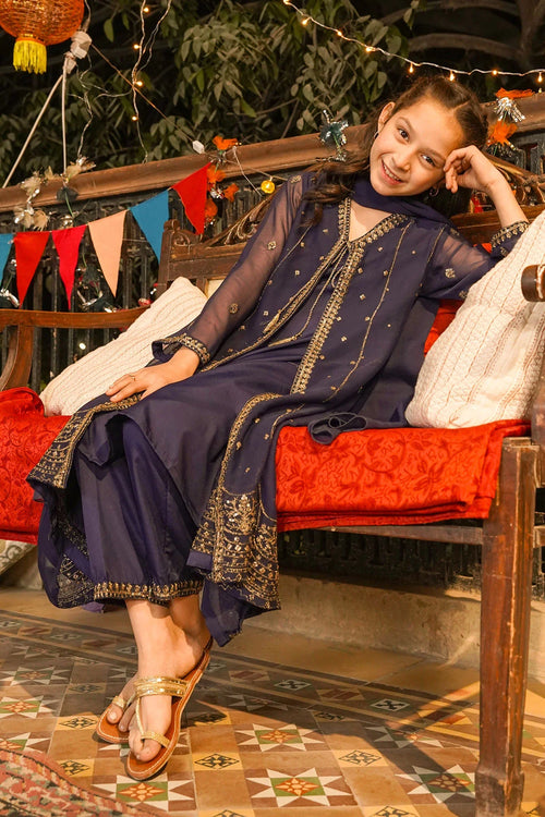 Girl in navy blue embroidered kurta with gold detailing, sitting on a decorated bench for festive occasions.