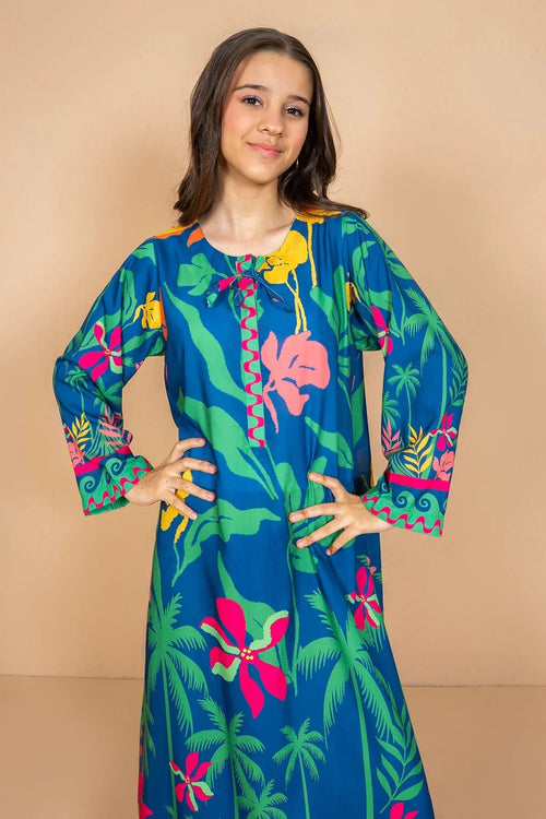 Girl wearing vibrant tropical print dress with palm trees and flowers, stylish summer outfit for teens